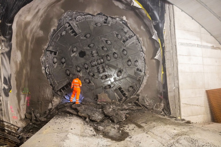 Ein Tunnelbauarbeiter begutachtet den Bohrschild der Tunnelbohrmaschine nach dem Durchstich